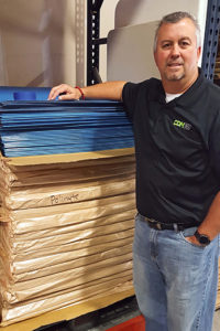 Rob Clark, partner, standing next to some of their hundreds of sheets of Polynite®—the best method for protecting floors from being damaged.